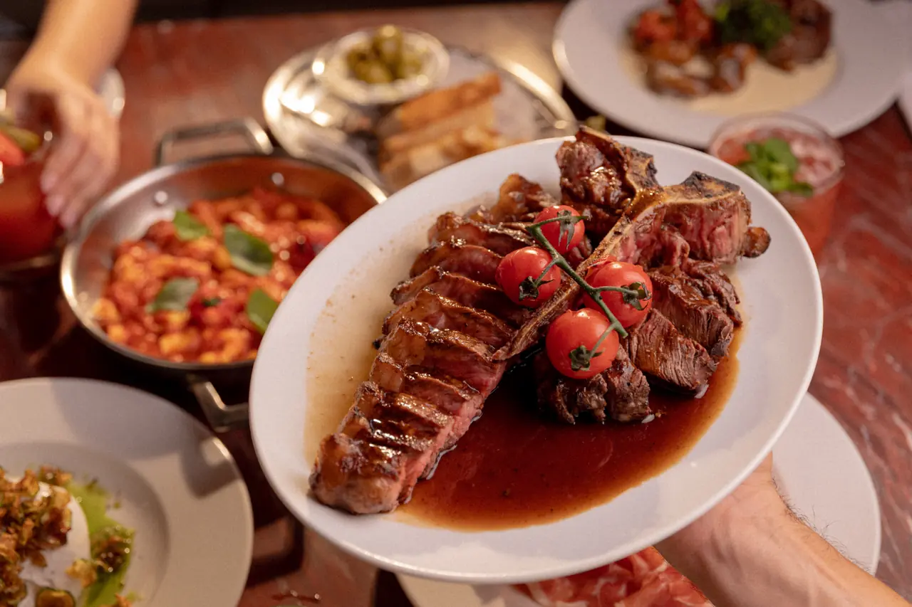 Carne fatiada com tomates sendo servida à mesa